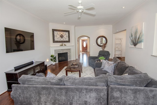living area with a ceiling fan, wood finished floors, arched walkways, and ornamental molding