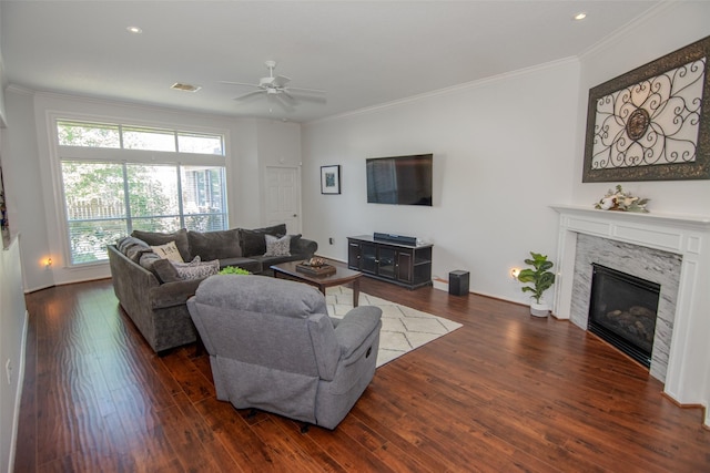 living area with wood finished floors, a high end fireplace, ceiling fan, ornamental molding, and recessed lighting