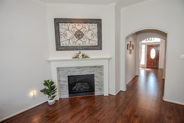 interior space featuring baseboards, wood finished floors, arched walkways, and crown molding