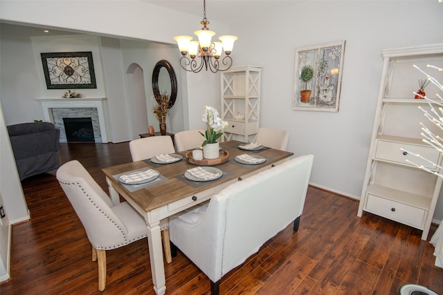 dining area with baseboards, dark wood-style floors, a fireplace, and a chandelier