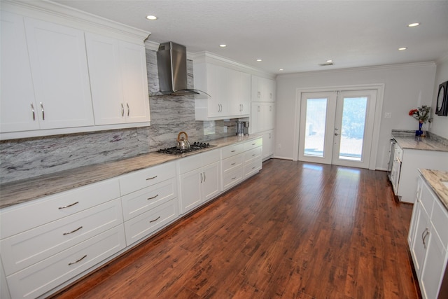 kitchen with tasteful backsplash, stainless steel gas cooktop, french doors, white cabinets, and wall chimney exhaust hood