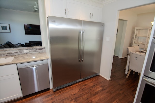 kitchen with dark wood-style flooring, a ceiling fan, appliances with stainless steel finishes, white cabinetry, and ornamental molding