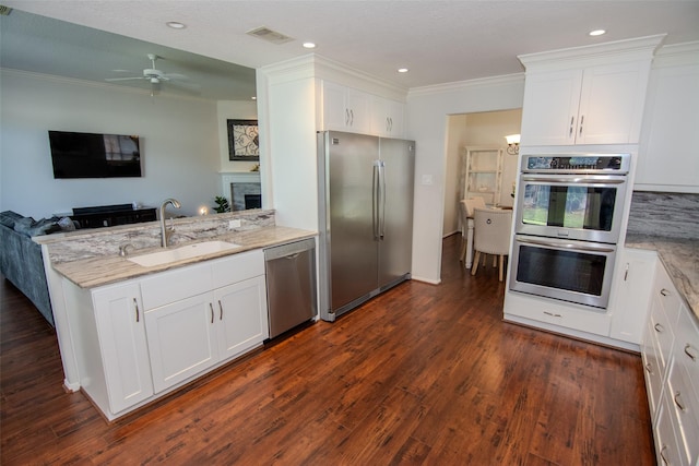 kitchen featuring stainless steel appliances, a sink, open floor plan, visible vents, and crown molding