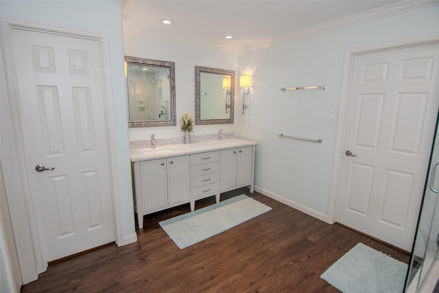 full bathroom featuring double vanity, wood finished floors, crown molding, and a sink