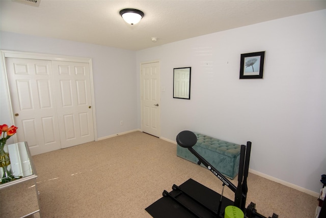 workout area featuring baseboards and light colored carpet