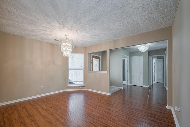 unfurnished room with dark wood-type flooring, a textured ceiling, and a chandelier