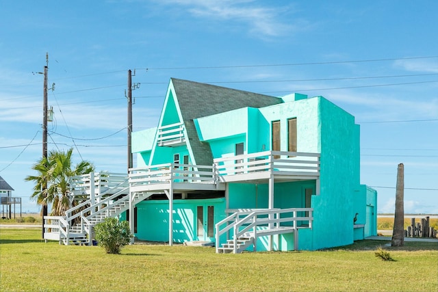 rear view of house featuring a wooden deck, stairs, roof with shingles, and a yard