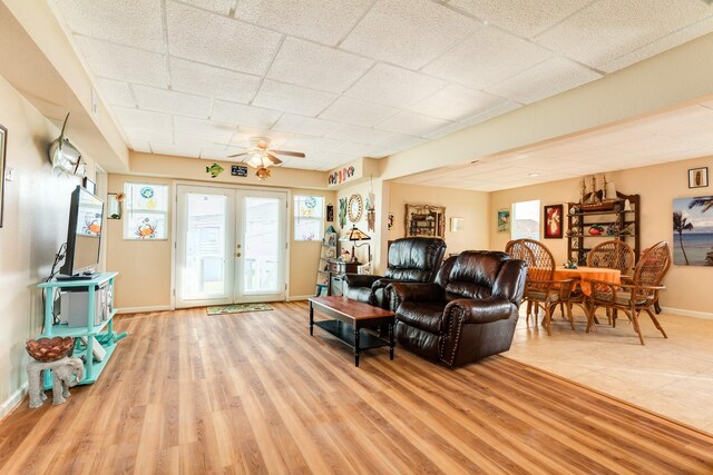 living room featuring a paneled ceiling, french doors, baseboards, wood finished floors, and ceiling fan