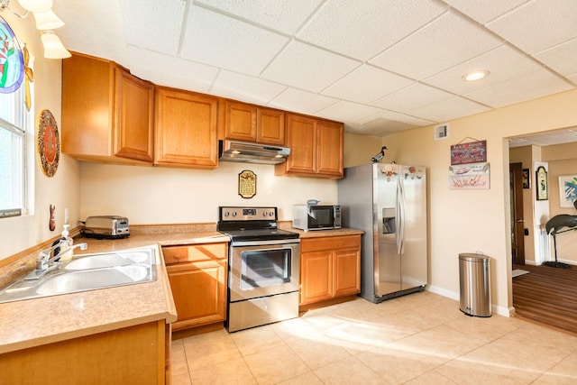 kitchen with a sink, appliances with stainless steel finishes, light countertops, under cabinet range hood, and recessed lighting