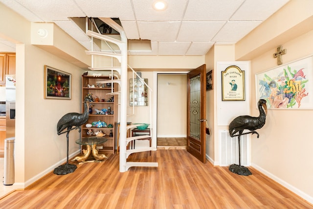 exercise room featuring baseboards, wood finished floors, and a drop ceiling
