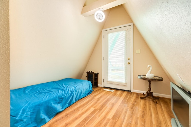 bedroom featuring lofted ceiling, baseboards, wood finished floors, and multiple windows