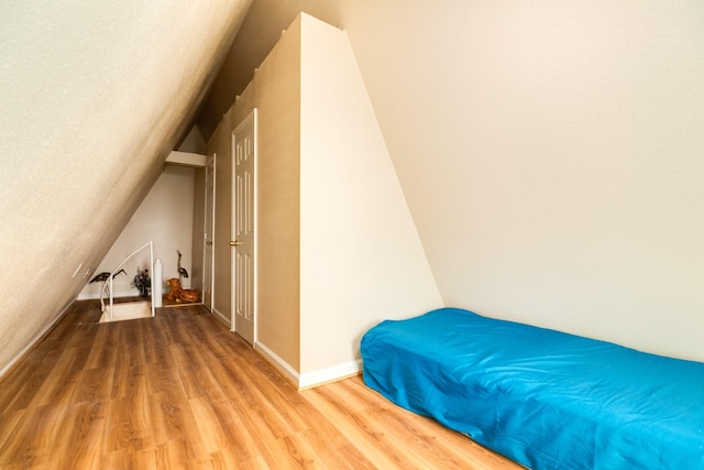 bedroom with baseboards, vaulted ceiling, and wood finished floors