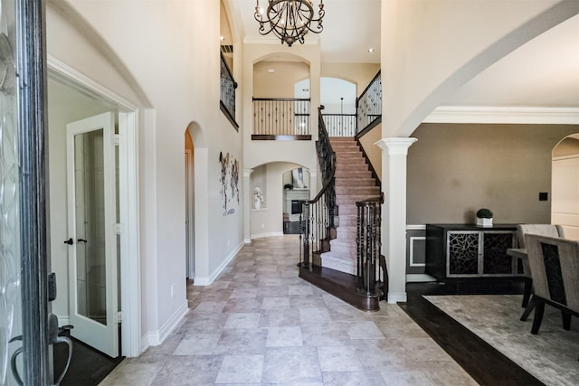 entrance foyer with arched walkways, baseboards, a high ceiling, and stairway