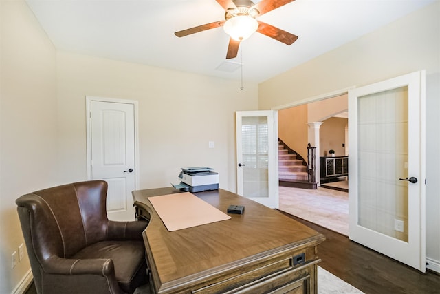 office space with dark wood-style floors, a ceiling fan, french doors, arched walkways, and decorative columns