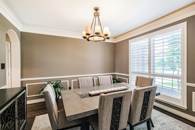 dining room with arched walkways, an inviting chandelier, ornamental molding, and dark wood-type flooring