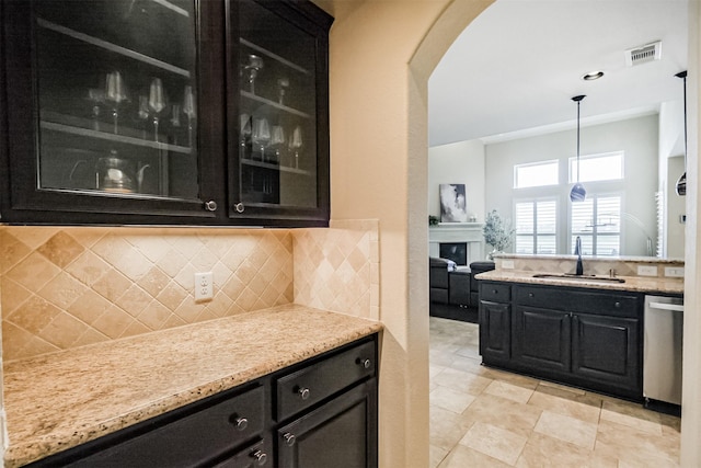 bar with visible vents, stainless steel dishwasher, a sink, arched walkways, and decorative backsplash