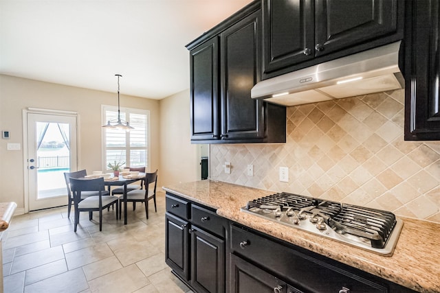 kitchen with stainless steel gas stovetop, dark cabinets, decorative light fixtures, backsplash, and under cabinet range hood