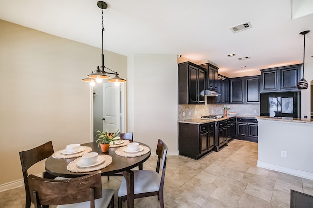 kitchen featuring tasteful backsplash, visible vents, stainless steel gas stovetop, pendant lighting, and under cabinet range hood