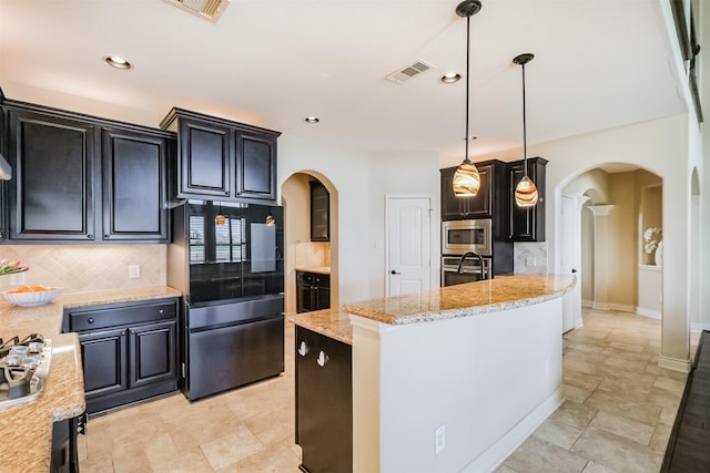 kitchen featuring visible vents, arched walkways, backsplash, and appliances with stainless steel finishes