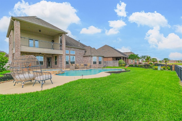 view of swimming pool featuring a lawn, a pool with connected hot tub, a patio area, and a fenced backyard