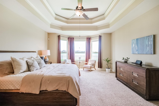 bedroom with a raised ceiling, ceiling fan, ornamental molding, and carpet