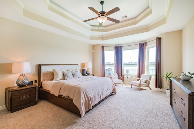 bedroom featuring a ceiling fan, crown molding, a tray ceiling, carpet flooring, and visible vents