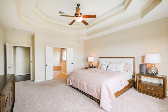 carpeted bedroom featuring a raised ceiling, visible vents, a ceiling fan, ornamental molding, and ensuite bathroom