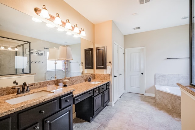 bathroom with a tile shower, a sink, and visible vents