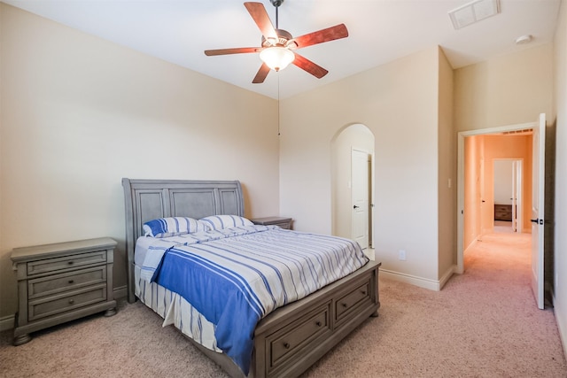 bedroom featuring arched walkways, baseboards, visible vents, light colored carpet, and ceiling fan