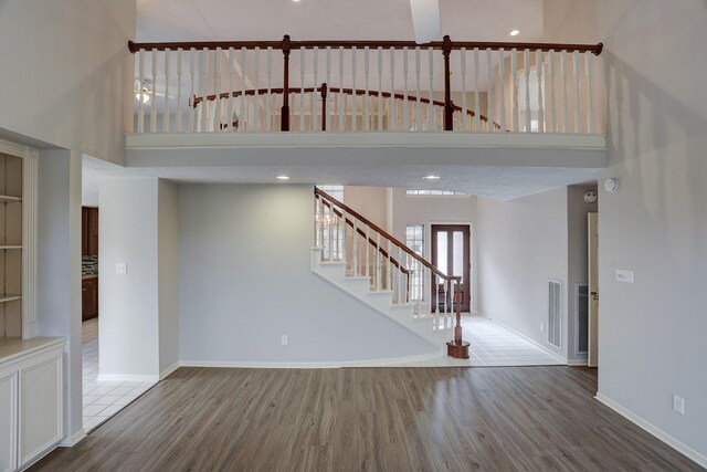 3126 Pebble Bay Dr, League City, TX 77573 - unfurnished living room with wood finished floors, stairs, a high ceiling, baseboards, and visible vents