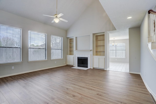 3126 Pebble Bay Dr, League City, TX 77573 - unfurnished living room with ceiling fan with notable chandelier, baseboards, a tile fireplace, and light wood-style flooring