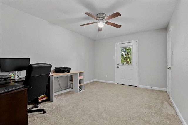 carpeted office space featuring ceiling fan and baseboards