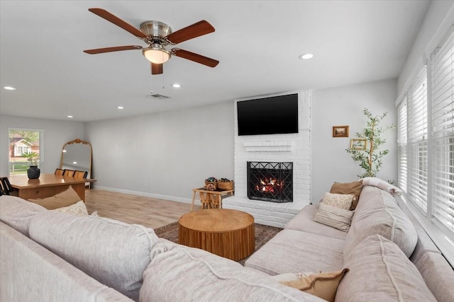 living room with wood finished floors, ceiling fan, a fireplace, visible vents, and recessed lighting
