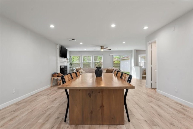 dining space featuring a fireplace, light wood finished floors, baseboards, and recessed lighting
