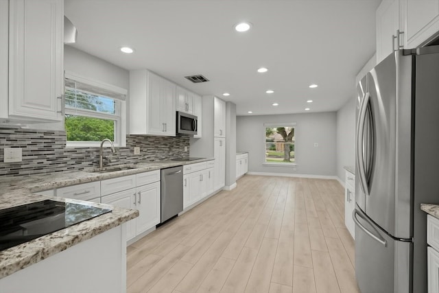 kitchen with decorative backsplash, appliances with stainless steel finishes, white cabinetry, and a sink