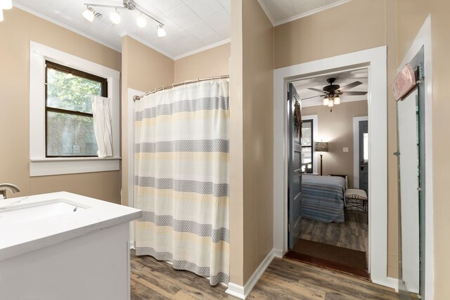 ensuite bathroom featuring a shower with curtain, wood finished floors, ceiling fan, and ornamental molding