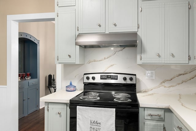 kitchen with tasteful backsplash, light stone counters, range with electric cooktop, under cabinet range hood, and white cabinetry