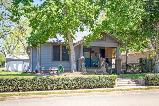 view of front of house featuring a detached garage, fence, and a porch