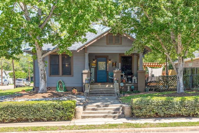 view of front of property featuring a porch, roof with shingles, and fence