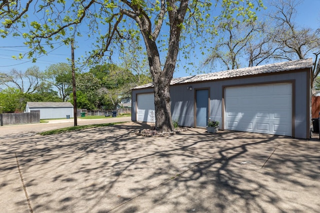 exterior space with a garage, fence, and an outbuilding