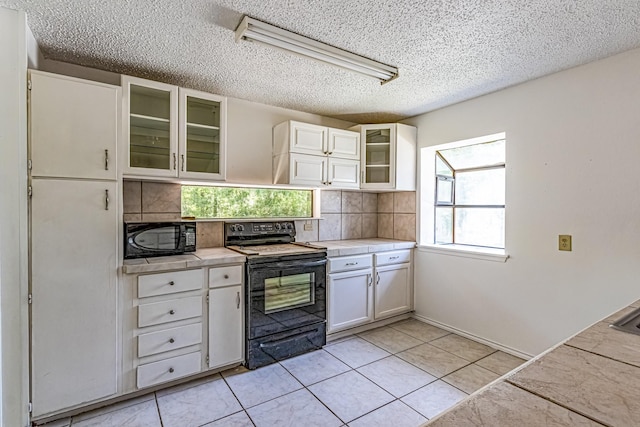 kitchen with black appliances, decorative backsplash, a textured ceiling, and light countertops