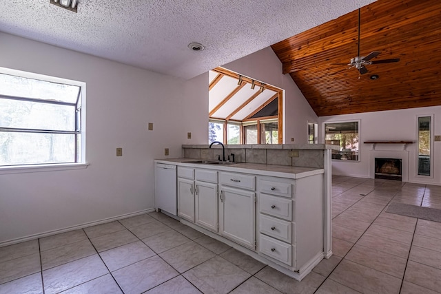 kitchen with a peninsula, a sink, open floor plan, dishwasher, and light tile patterned floors