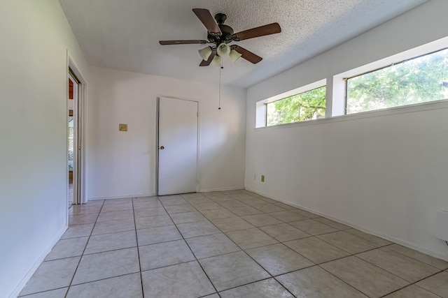 empty room featuring a ceiling fan, baseboards, and light tile patterned floors