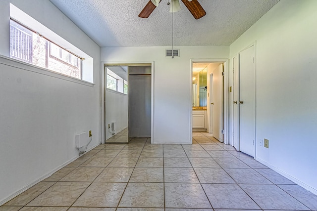 unfurnished bedroom with ceiling fan, a textured ceiling, visible vents, and a closet