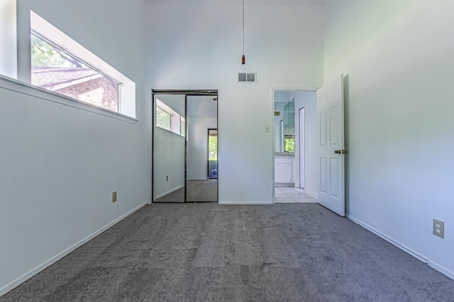 unfurnished bedroom with visible vents, carpet flooring, baseboards, and a towering ceiling