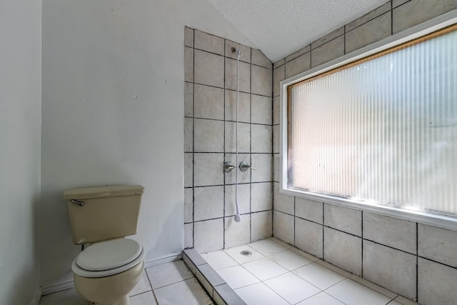 bathroom featuring a textured ceiling, a tile shower, toilet, vaulted ceiling, and tile patterned flooring