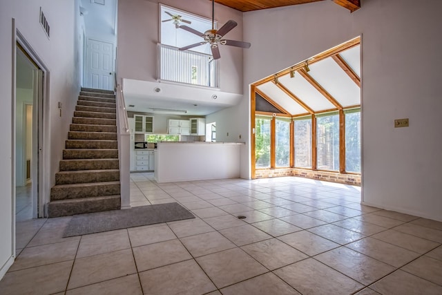 unfurnished living room with a ceiling fan, tile patterned floors, stairs, a high ceiling, and visible vents