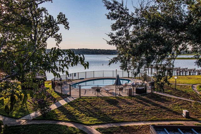 view of swimming pool featuring fence, a water view, and a fenced in pool
