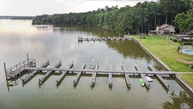 view of dock featuring a view of trees, a lawn, and a water view