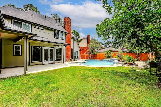 view of yard with french doors, a patio, and a pool with connected hot tub